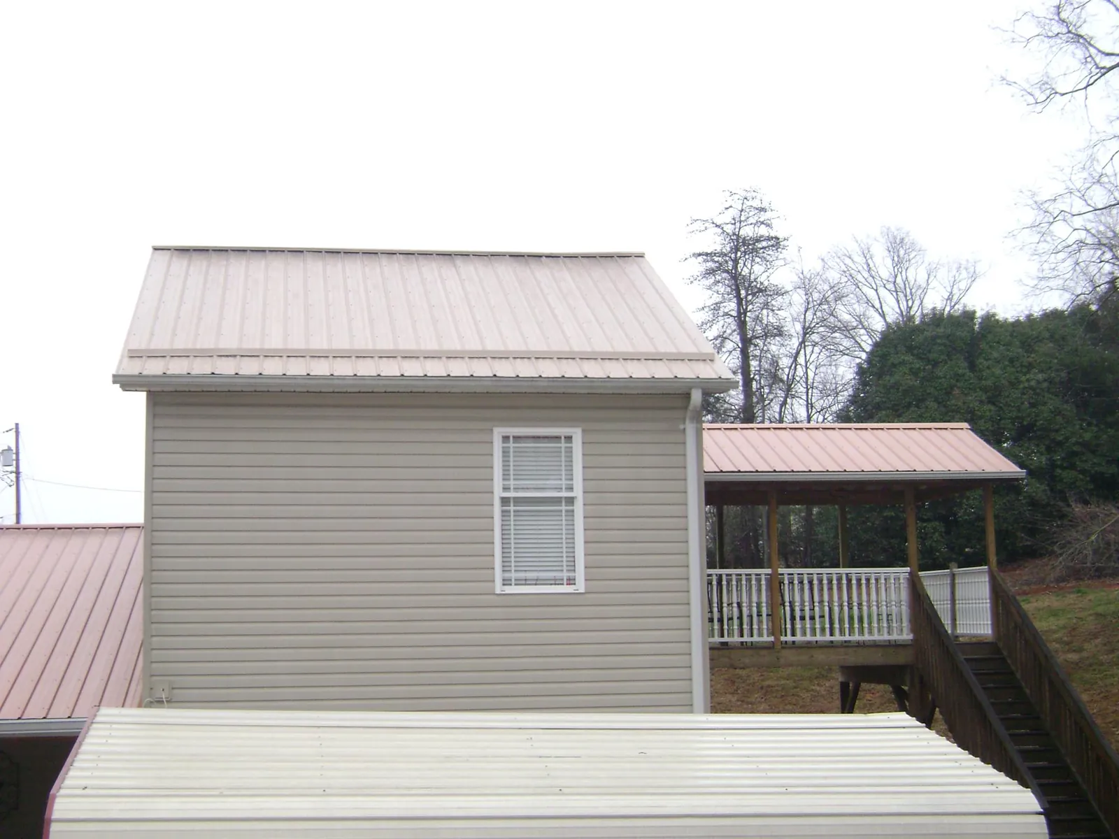 Tan metal roofs on a two story addition and attached porch, from a Roof Replacement job in Waco